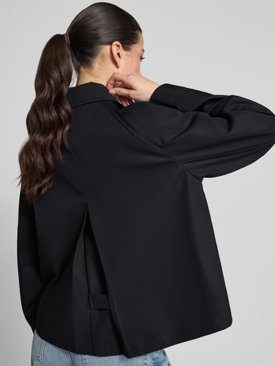 Kobiece model prezentuje Relaxed Fit Trenchcoat aus reiner Baumwolle von Tommy Hilfiger, efekt: jednolity kolor, krój relaxed fit, wykładany kołnierz, listwa guzikowa, długość krótki, detal z logo, proste zakończenie rękawów, hydrofobowy, splot twill, materiał: bawełna, widok całej sylwetki z tyłu.