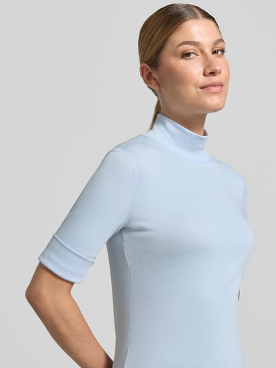 Frauenmodel trägt Slim Fit T-Shirt aus Baumwoll-Mix mit Stehkragen von Marc Cain in Hellblau, elastisch, 1/2-Arm, Nahaufnahme Oberkörper.