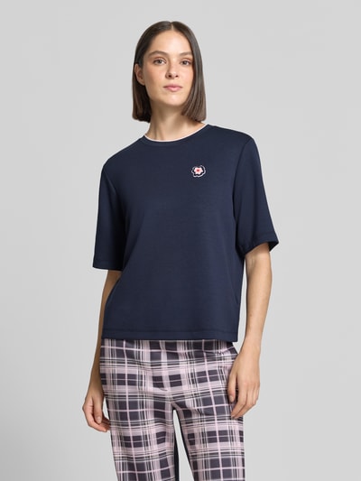 Modelka nosi Relaxed Fit T-Shirt aus Viskose-Mix von Marc Cain, granatowy kolor, detal z logo, okrągły dekolt, damski t-shirt, długość tyłu w rozmiarze 36: 54 cm, mieszanka wiskozy, krój relaxed fit, widok całej sylwetki z przodu.
