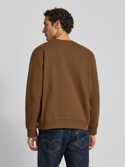 Männermodel trägt braunes Sweatshirt mit Rundhalsausschnitt aus Baumwolle von Wood Wood, Modell 'Colter', Ganzkörperansicht Rückansicht.