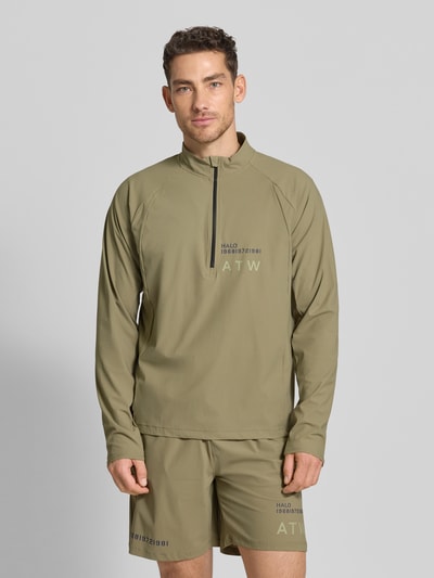 Mannenmodel draagt Funktionsshirt mit Stehkragen und Reißverschluss Modell 'AIR' van HALO in olijfgroen, regular fit, label-print, materiaal-mix met stretch, vooraanzicht van het volledige lichaam.