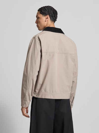 Męski model nosi Regular Fit Ranch-Jacke aus reiner Baumwolle od Tommy Jeans, jednokolorowa, wykładany kołnierz ze sztruksu, długi rękaw, zamek błyskawiczny, wyhaftowane logo, regulacja szerokości, kieszenie na zamek, bawełna; widok całej sylwetki z tyłu.