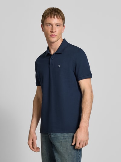 Männermodel trägt Straight Fit Poloshirt mit Label-Stitching von Calvin Klein Jeans in Dunkelblau, Reine Baumwolle, Nahaufnahme Oberkörper.