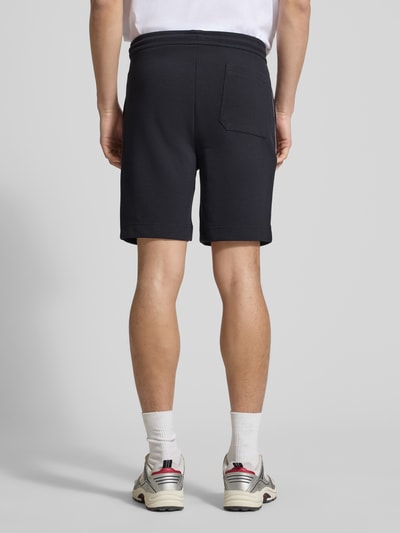 Männermodel trägt Regular Fit Shorts aus Baumwoll-Mix Modell 'T_JOIN Headlo' von BOSS Green in Schwarz, Rückansicht Ganzkörperansicht.