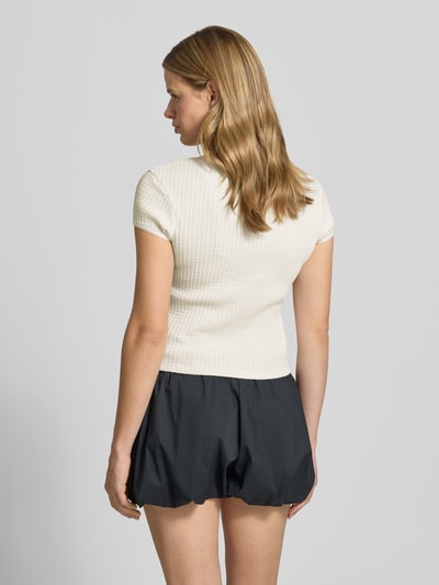 Frauenmodel trägt Damen T-Shirt aus Reine Baumwolle, Slim-Fit, Modell 'AJOUR' von REVIEW, Struktur mit durchgehender Knopfleiste, Rückenlänge 49 cm, Kurzärmelig, Rundhalsausschnitt, Creme, Schwarz, Ganzkörperansicht Rückansicht.