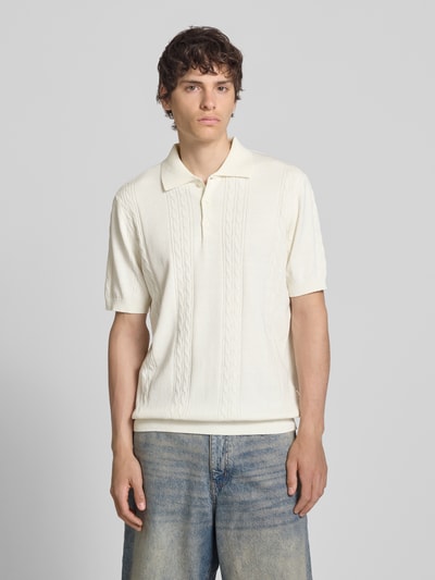 Männermodel trägt Slim Fit Strick-Poloshirt mit Zopfmuster Modell 'Miller' von Redefined Rebel, cremefarben, Baumwoll-Mix, Ganzkörperansicht von vorne.