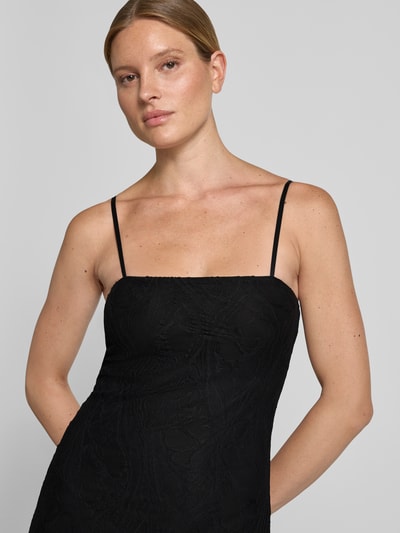 Frauenmodel trägt Maxikleid aus Spitze Modell 'EVELYN' von GUESS in Schwarz, figurbetont, feine Textur, Nahaufnahme Oberkörper.