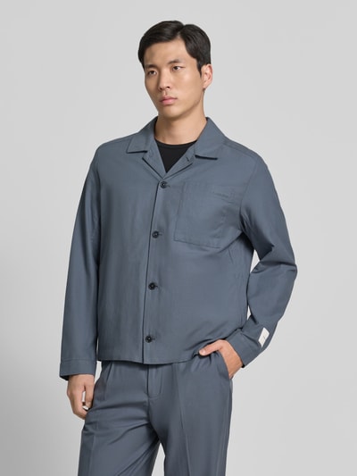 Männermodel trägt Oversized Hemdjacke aus Baumwoll-Lyocell-Mix von CK Calvin Klein in Unifarbe, Twill-Textur, Ganzkörperansicht von vorne