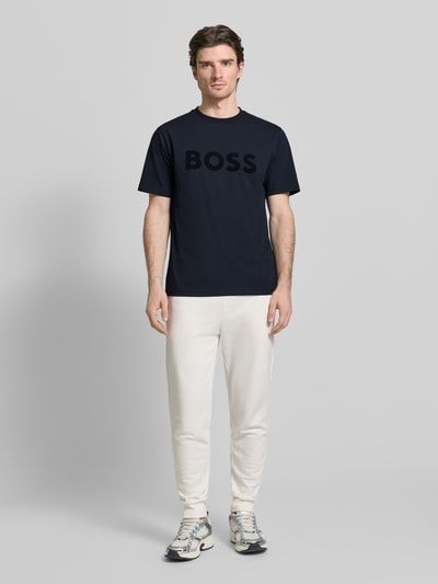 Männermodel trägt Regular Fit T-Shirt aus Baumwoll-Mix Modell 'ICONIC' von BOSS Green in Dunkelblau, unifarben, Ganzkörperansicht von vorne.