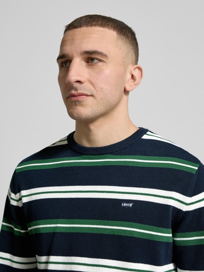 Männermodel trägt Regular Fit Sweatshirt aus reiner Baumwolle von Levi's®, Allover-Streifenmuster in Blau, Weiß und Grün, Nahaufnahme Oberkörper.