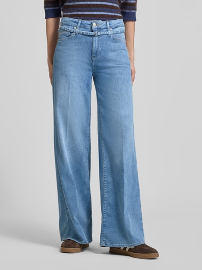 Kobieta nosi Wide Fit Jeans mit Lyocell-Anteil Modell 'Sventy' od Raffaello Rossi, mieszanka bawełny i lyocellu, 5 kieszeni, odpinana materiałowa tasiemka, wzór z logo, zapięcie na guzik i zamek błyskawiczny, szerokość w rozmiarze 36: 38 cm, długość wewnętrzna nogawki w rozmiarze 36: 80 cm, jasnoniebieski denim, tekstura gładka, całkowity widok z przodu.