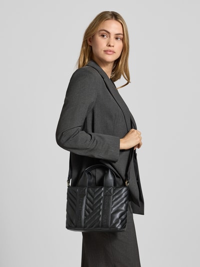 Frauenmodel trägt Henkeltasche mit abnehmbarem Schulterriemen Modell 'BECKY QL_TOTE MINI' von HUGO in Optik: Unifarben aus Kunstleder, Struktur, Label Stitching, Label-Schriftzug, Label-Prägung, Tragehenkel, Reißverschluss, Hauptfach, Ganzkörperansicht von vorne.