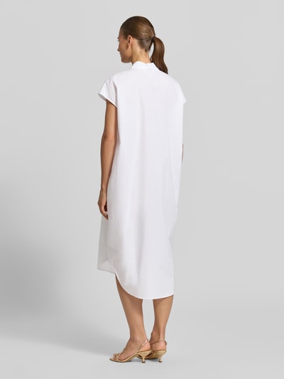 Frauenmodel trägt knielanges Hemdblusenkleid mit kurzer Knopfleiste von Christian Berg Woman aus Reine Baumwolle, Loose-Fit, Hemdblusenkragen, Brusttasche, abgerundeter Saum, verlängerter Rücken, Farbe Weiß, glatte Textur, Ganzkörperansicht Rückansicht, Rückenlänge bei Größe 36: 116 cm, Brustweite: 62 cm.