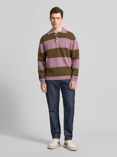 Männermodel trägt Strickpullover mit Polo-Kragen Modell 'Kimse' von Wood Wood in Rosa-Oliv-Streifen aus Baumwoll-Mix, Ganzkörperansicht von vorne.