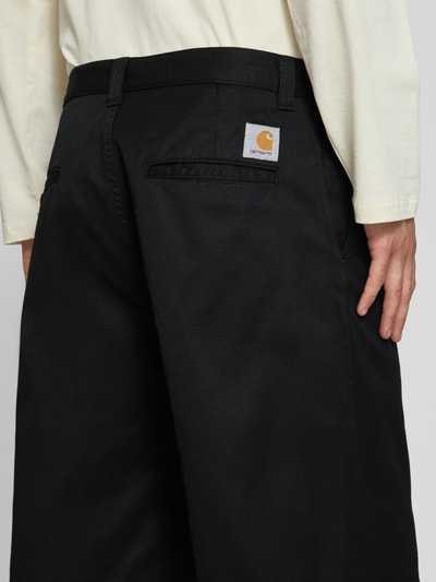 Männermodel trägt Bermudas mit Baumwoll-Anteil Modell 'Brader' von Carhartt Work In Progress in Schwarz, Material-Mix, Relaxed Fit, Nahaufnahme Rückansicht.