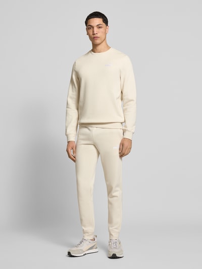 Männermodel trägt Sweatpants mit Label-Stitching von PUMA PERFORMANCE in Beige, Baumwoll-Mix, Regular-Fit, Ganzkörperansicht von vorne.