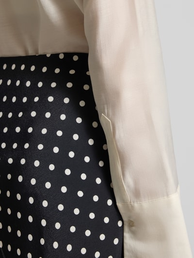 Frauenmodel trägt Maxirock mit blickdichtem Unterrock Modell 'Viso' von Neo Noir, schwarzer Stoff mit weißen Punkten, glatte Textur, Nahaufnahme Oberkörper. Bundweite bei Größe 36 beträgt 39 cm, Gesamtlänge 111 cm.