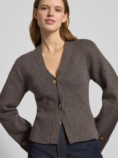 Vrouwenmodel draagt Slim Fit Cardigan met Wol-Aandeel in Breilook van Gina Tricot, V-hals, trompetmouwen, sierknopen, close-up bovenlichaam.