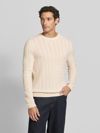 Männermodel trägt Slim Fit Strickpullover aus reinem Kaschmir mit Zopfmuster von Christian Berg Men, cremefarben, Nahaufnahme Oberkörper. Gerippte Abschlüsse, Rundhalsausschnitt, langärmlig, Textur und Muster sind gut erkennbar.