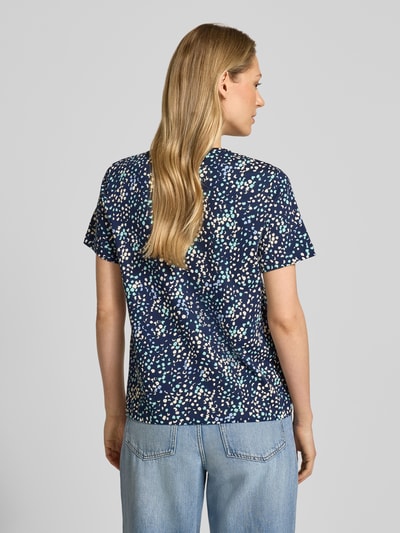 Modelka nosi Regular Fit T-Shirt aus reiner Baumwolle von Tom Tailor, efekt: wzór w kropki na całej powierzchni, aplikacja: naszywka z logo, okrągły dekolt, rękaw: krótki, zakończenie rękawów proste, wykończenie materiału: dżersej, materiał: czysta bawełna, zdjęcie całej sylwetki z tyłu.