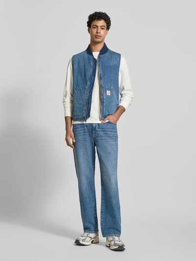 Männermodel trägt Regular Fit Weste in Denim-Optik Modell 'Sansome' von Levi's®, Stehkragen, Logo-Patch, Kängurutasche, Ganzkörperansicht von vorne.