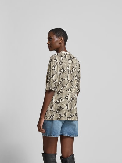 Frauenmodel trägt Regular Fit T-Shirt aus reiner Baumwolle von Anine Bing mit Schlangenprint, Rundhalsausschnitt, Halbarm, Rückenlänge 65 cm, Ganzkörperansicht Rückansicht.