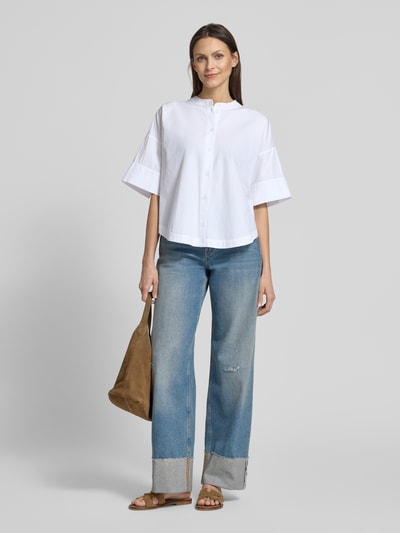 Frauenmodel trägt Boxy Fit Bluse mit Rundhalsausschnitt Modell 'Fibana' von OPUS PANTS, Reine Baumwolle, weiße Farbe, Knopfleiste, Rückenlänge 65 cm, Ärmellänge 27 cm, lockere Passform, weiche Textur, Ganzkörperansicht von vorne.