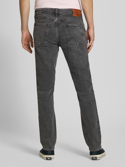 Männermodel trägt Slim Fit Jeans aus Baumwoll-Mix von Calvin Klein Jeans, grauer Denim mit Waschung, Ganzkörperansicht Rückansicht.