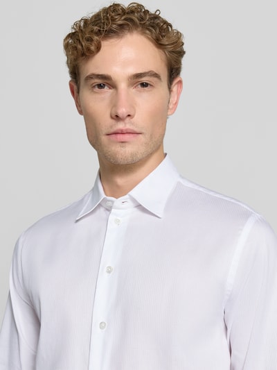 Männermodel trägt Slim Fit Business-Hemd aus reiner Baumwolle von Emporio Armani in Weiß mit Kentkragen, Nahaufnahme Oberkörper.