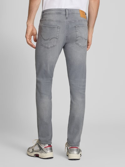 Männermodel trägt graue Slim Fit Jeans aus Baumwoll-Mix Modell 'Glenn' von JACK & JONES, 5-Pocket-Design, Ganzkörperansicht Rückansicht.