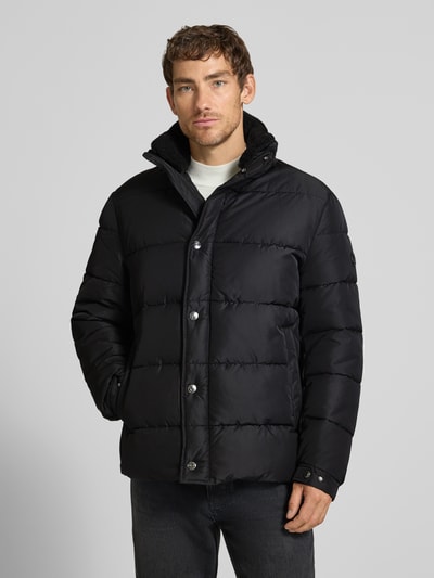 Männermodel trägt eine schwarze Regular Fit Steppjacke mit Logo-Detail Modell 'Newton' von JOOP! COLLECTION, Ganzkörperansicht von vorne.