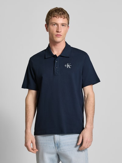 Männermodel trägt Easy Fit Poloshirt mit Polokragen von Calvin Klein Jeans, Reine Baumwolle, Label-Stitching, navyblau, Ganzkörperansicht von vorne.