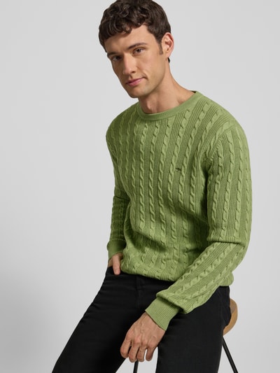 Männermodel trägt Strickpullover mit Zopfmuster und Label-Stitching von Fynch-Hatton in Grün, Reine Baumwolle, Slim-Fit, Nahaufnahme Oberkörper.