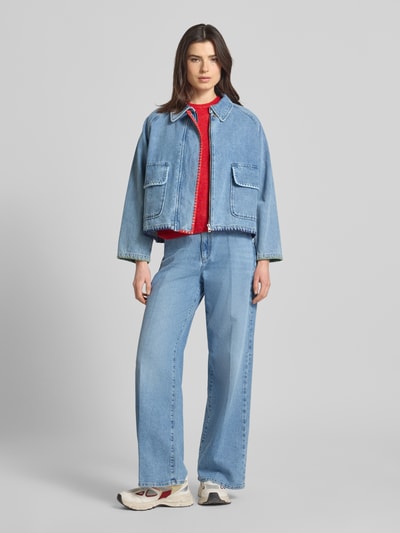 Kobiece modelka nosi kurtkę jeansową z haftem i kieszeniami z patką 'Jeansjacke mit Stitching und Pattentaschen' od Amber & June, z czystej bawełny, pudełkowy krój, wykładany kołnierz, długość tyłu w rozmiarze 36: 56 cm, szerokość ramion w rozmiarze 36: 46 cm, szerokość klatki piersiowej w rozmiarze 36: 63 cm, długość rękawów w rozmiarze 36: 55 cm, jasnoniebieski denim, prosty fason, struktura materiału widoczna, cała sylwetka z przodu.