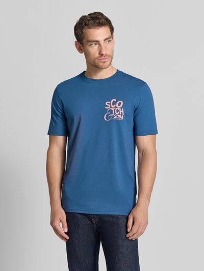 Männermodel trägt Regular Fit T-Shirt mit Logo-Print van Scotch & Soda in blauw met logoprint, puur katoen, ronde hals, ruglengte maat M 73 cm. Ganzkörperansicht van voren.