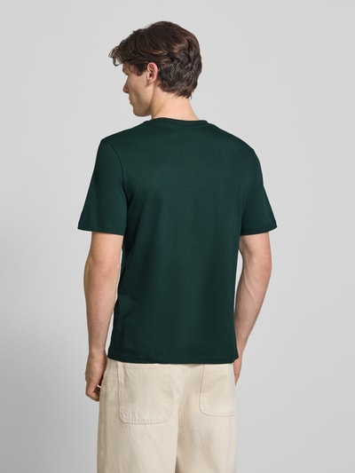 Männermodel trägt Regular Fit T-shirt met logoprint model 'Munk' van JACK & JONES, puur katoen, ruglengte maat M 74 cm, Ganzkörperansicht Rückansicht.