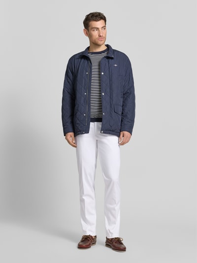 Männermodel trägt Regular Fit Chino mit Eingrifftaschen Modell 'Peaker' von Hiltl aus Baumwoll-Elasthan-Mix in Weiß, Ganzkörperansicht von vorne, Herren Chino, Bundweite bei Größe 50: 45 cm, Innenbeinlänge bei Größe 50: 84 cm.
