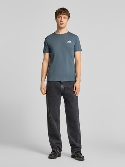 Męski model trägt t-shirt mit Label-Details Modell 'BASIC' von Alpha Industries z bawełny, prosty krój, okrągły dekolt, długość tyłu w rozmiarze M 67 cm, całkowity widok z przodu.