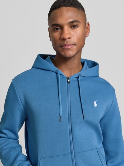 Mężczyznamodel nosi Regular Fit Sweatjacke aus Baumwoll-Mix od Polo Ralph Lauren, efekt: jednolity kolor, krój regular fit, wyhaftowane logo, kaptur z tunelem, długi rękaw, wykończenie: dzianina dresowa, mieszanka bawełny, zamek błyskawiczny, zapięcie: zamek błyskawiczny, kolor niebieski, z przodu, zbliżenie na górną część ciała.