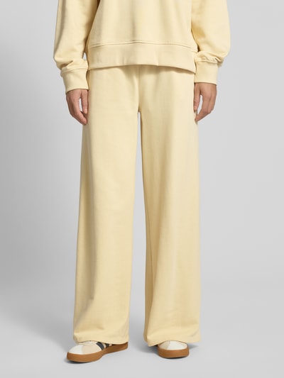 Kobiece modelka ma na sobie Wide Fit Sweatpants mit elastische Bund od Gina Tricot, bawełniany miks, krój wide fit, elastyczny pas, relaxed fit, szerokość wewnętrzna nogawki w rozmiarze S: 76 cm, jasny żółty kolor, gładka tekstura, widok całego ciała z przodu.
