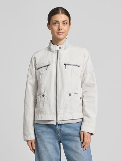 Frauenmodel trägt hellgraue Jacke mit Zweiwege-Reißverschluss von Amber & June, Stehkragen, Taschendetails, Ganzkörperansicht von vorne.