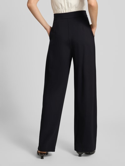 Frauenmodel trägt Bundfaltenhose mit Eingrifftaschen von Emporio Armani, schwarze weite Hose, glatte Textur, Ganzkörperansicht Rückansicht.