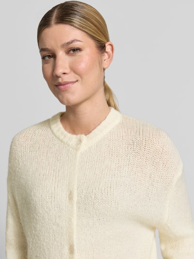Frauenmodel trägt Cardigan mit Alpaka-Anteil und Rundhalsausschnitt Modell 'OTIA' von b.young in Creme, feine Stricktextur, Nahaufnahme Oberkörper. Materialmix, Regular Fit, Knopfleiste, S-Größe: Rücken 52 cm, Ärmel 58 cm.