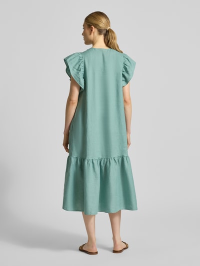 Kobiece modelka nosi Leinenkleid mit Rüschen und Rundhalsausschnitt von Christian Berg Woman, len, linia a, sukienka midi, okrągły dekolt, falbany, długość tyłu w rozmiarze 36: 118 cm, szerokość w rozmiarze 36: 52 cm, długość rękawów w rozmiarze 36: 15 cm, matowa tekstura, jasny zielony kolor, całkowity widok z tyłu.