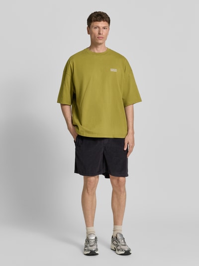 Männermodel trägt T-Shirt mit Logo-Print Modell 'GIXY' von American Vintage in Olivgrün, Loose Fit, reine Baumwolle, Ganzkörperansicht von vorne