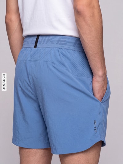 Männermodel trägt hellblaue Regular Fit Sportshorts mit Dri-FIT-Technologie von Nike Training, strukturierte Oberfläche, Ganzkörperansicht Rückansicht, KI-modifiziertes Bild.