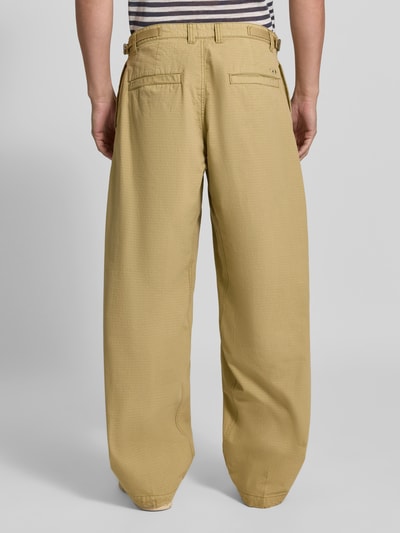 Männermodel trägt Straight Fit Hose aus reiner Baumwolle von Diesel in Beige mit Gesäßtaschen, Rückansicht, Ganzkörperansicht.