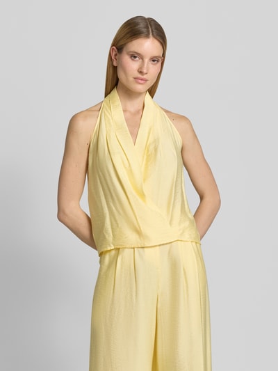 Frauenmodel trägt Regular Fit Top aus Viskose-Mix Modell 'Salma' von GUIDO MARIA KRETSCHMER WOMAN, Wickel-Optik, ärmelloses Design, Neckholder, V-Ausschnitt, Raffungen, Rückenlänge bei Größe 36: 55 cm, hellgelb, glatte Textur, Ganzkörperansicht von vorne.