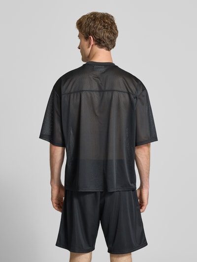Männermodel trägt T-Shirt aus Mesh mit Logo-Print von REVIEW, schwarzes Mesh, Loose-Fit, Rundhalsausschnitt, Rückenlänge 66 cm, Ganzkörperansicht Rückansicht.