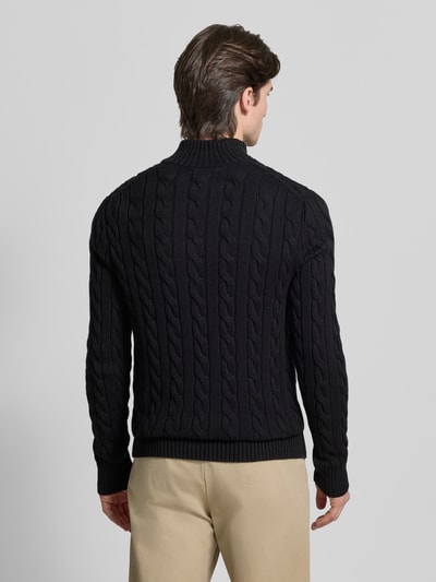 Männermodel trägt Regular Fit Troyer aus reiner Baumwolle von Polo Ralph Lauren in Schwarz mit Zopfmuster, Strickoptik, gerippt, Ganzkörperansicht Rückansicht.